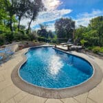 concrete pool and patio with surrounding fence