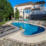 concrete pool and patio behind a residence