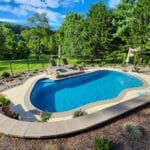 concrete pool and patio from retaining wall view