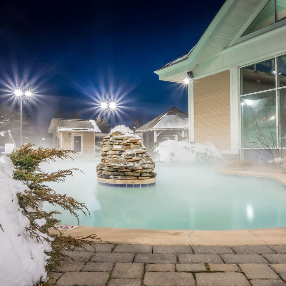 hot tubs and ingound heated pool at a mountain village in winter at night